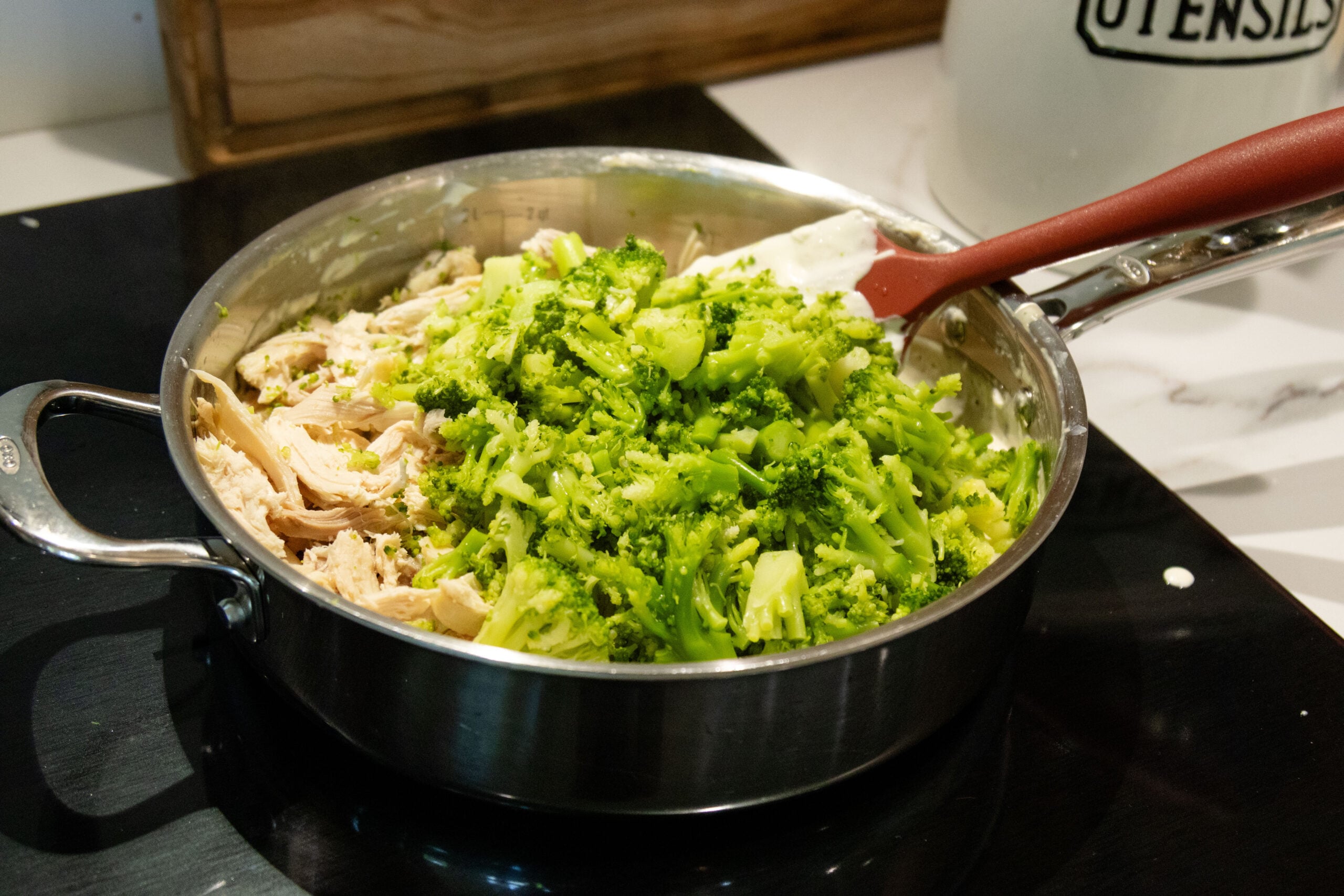 using a spatula to toss the chicken bacon broccoli mixture together