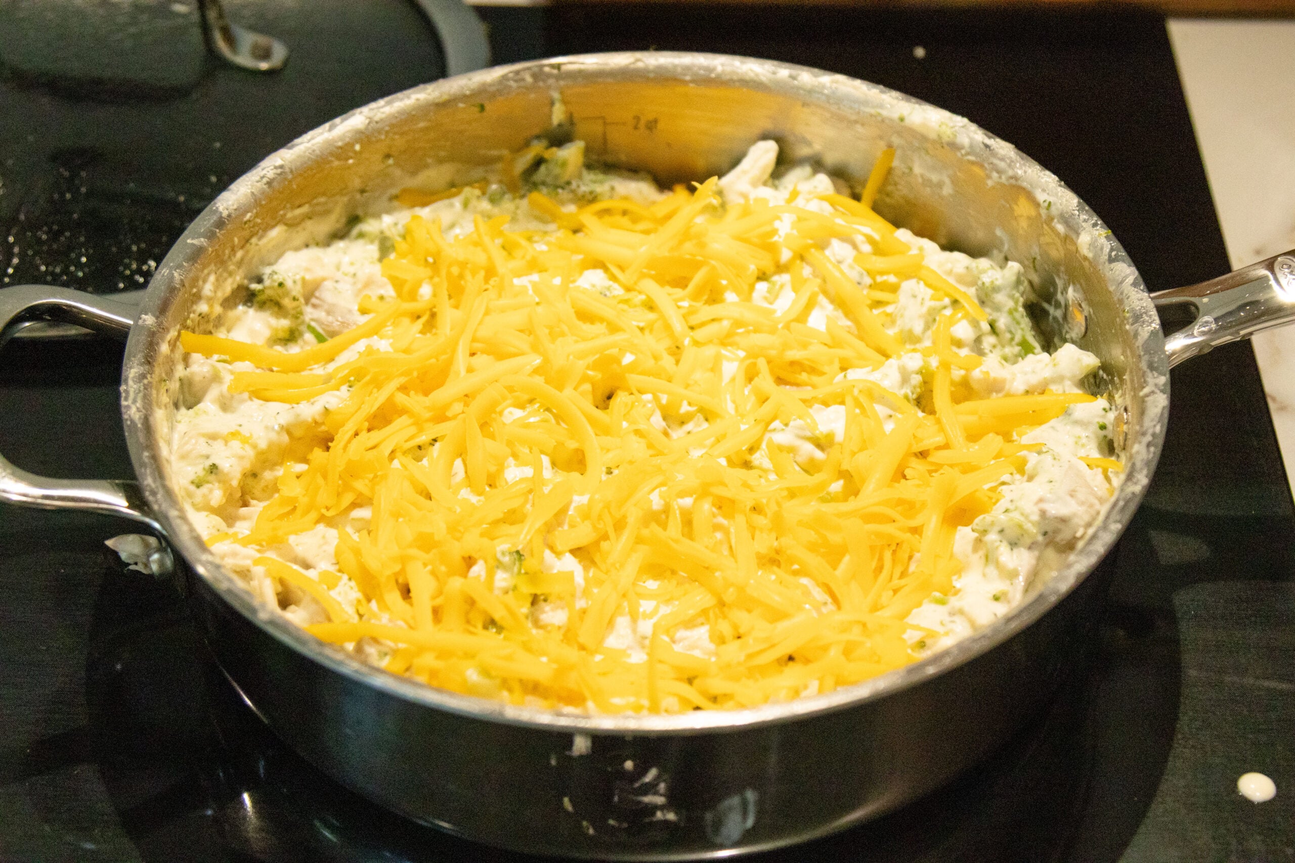 spreading the cheese on top of the skillet dinner