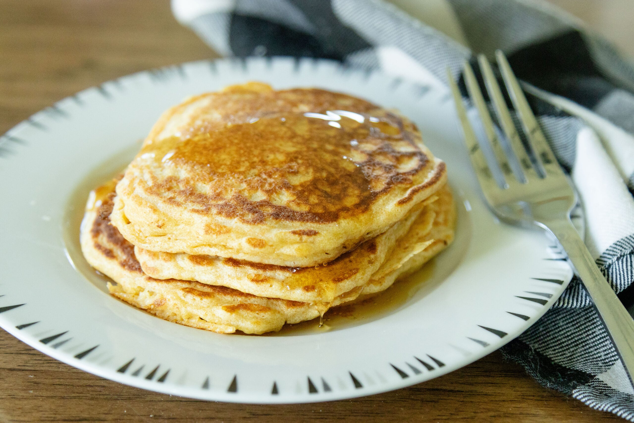 a stack of pancakes on a plate with maple syrup on top