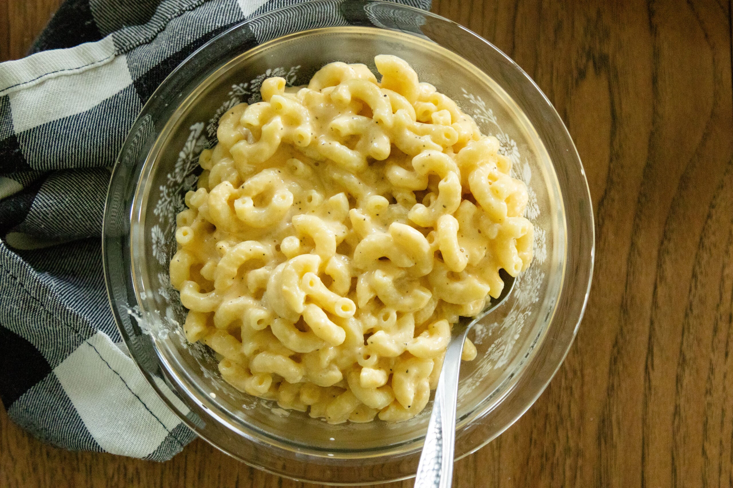 macaroni and cheese in a glass serving dish with a spoon stuck in the side