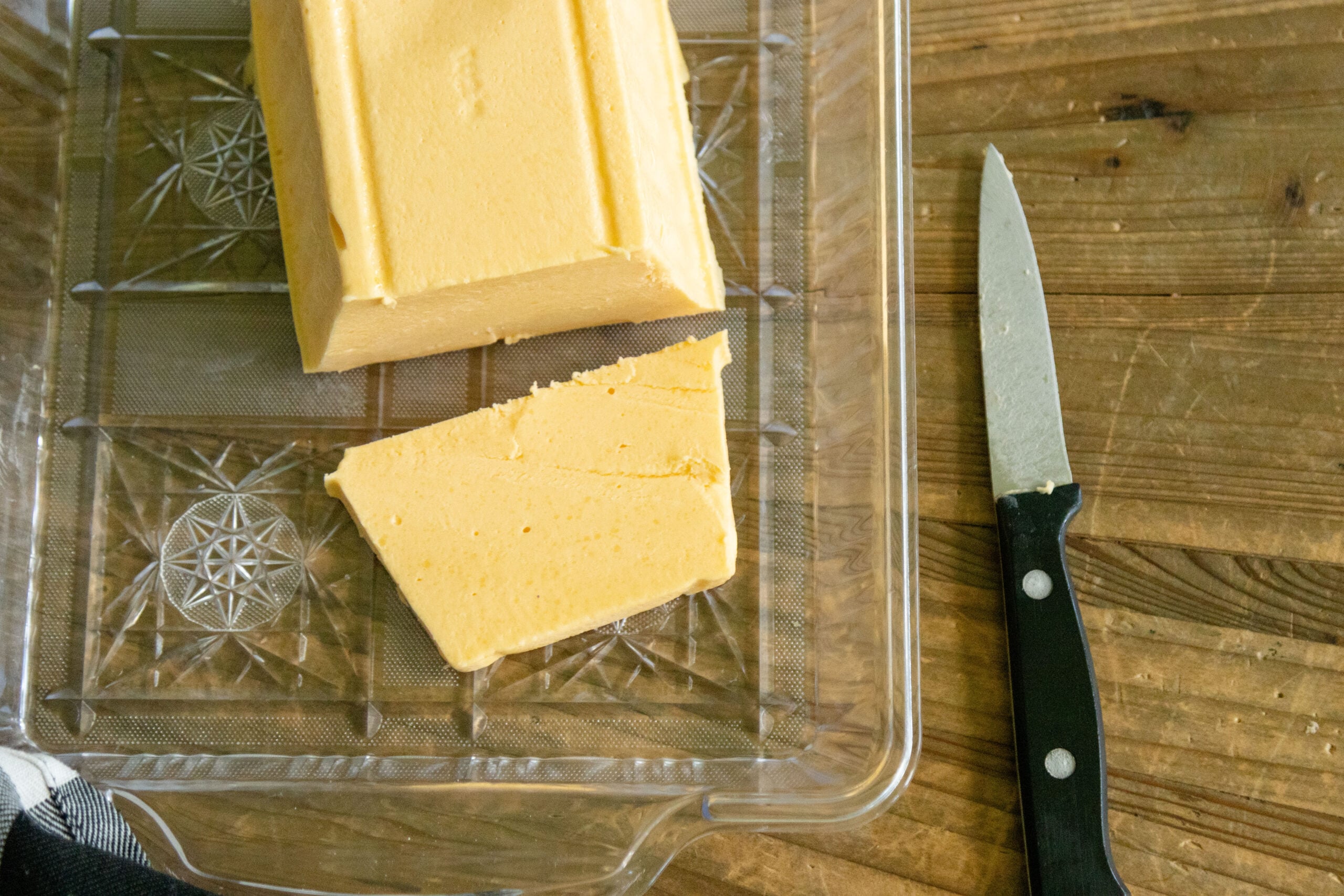 the finished block of velveeta cheese on a platter with a knife laying nearby