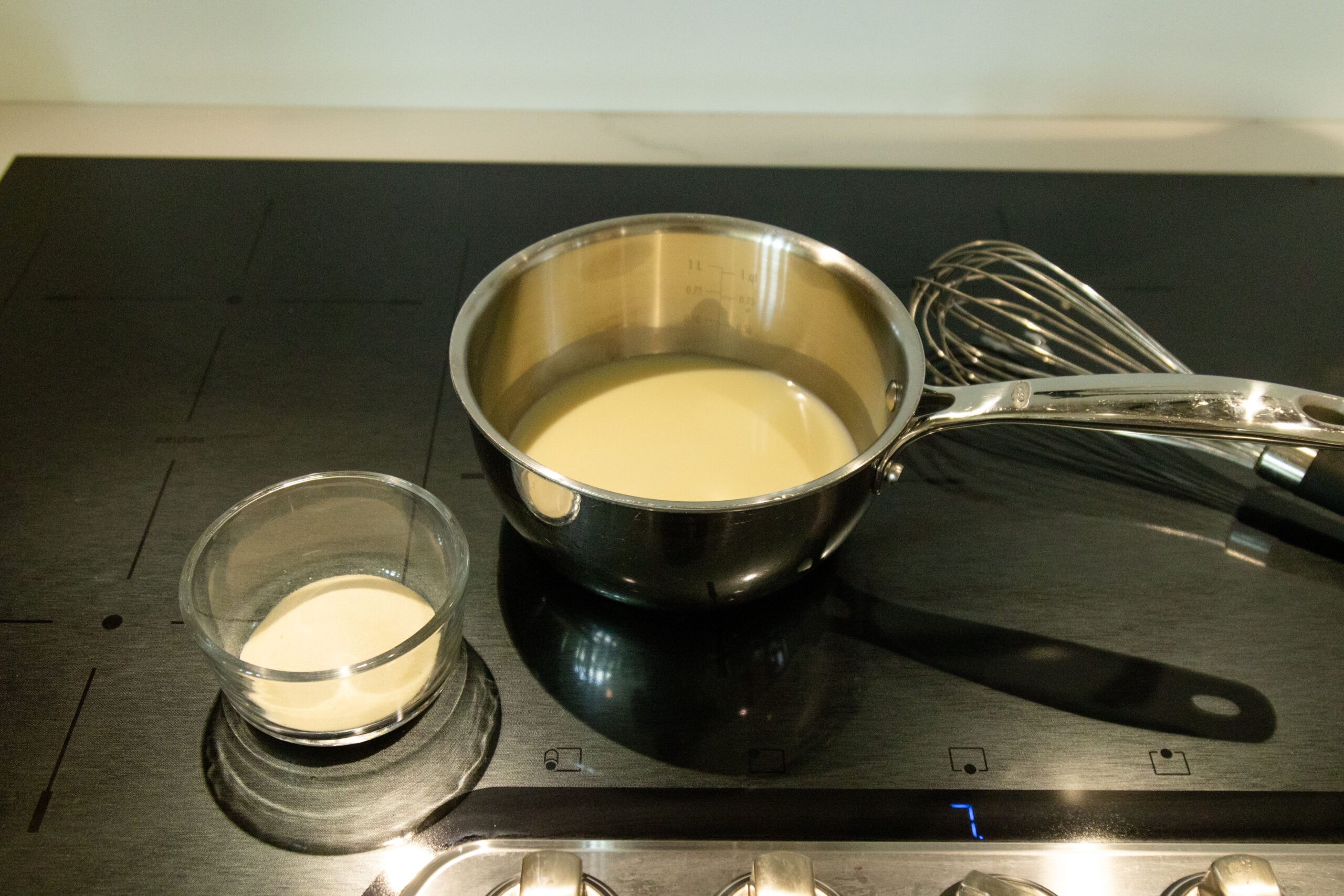 Milk heating in the saucepan with the gelatin sitting nearby