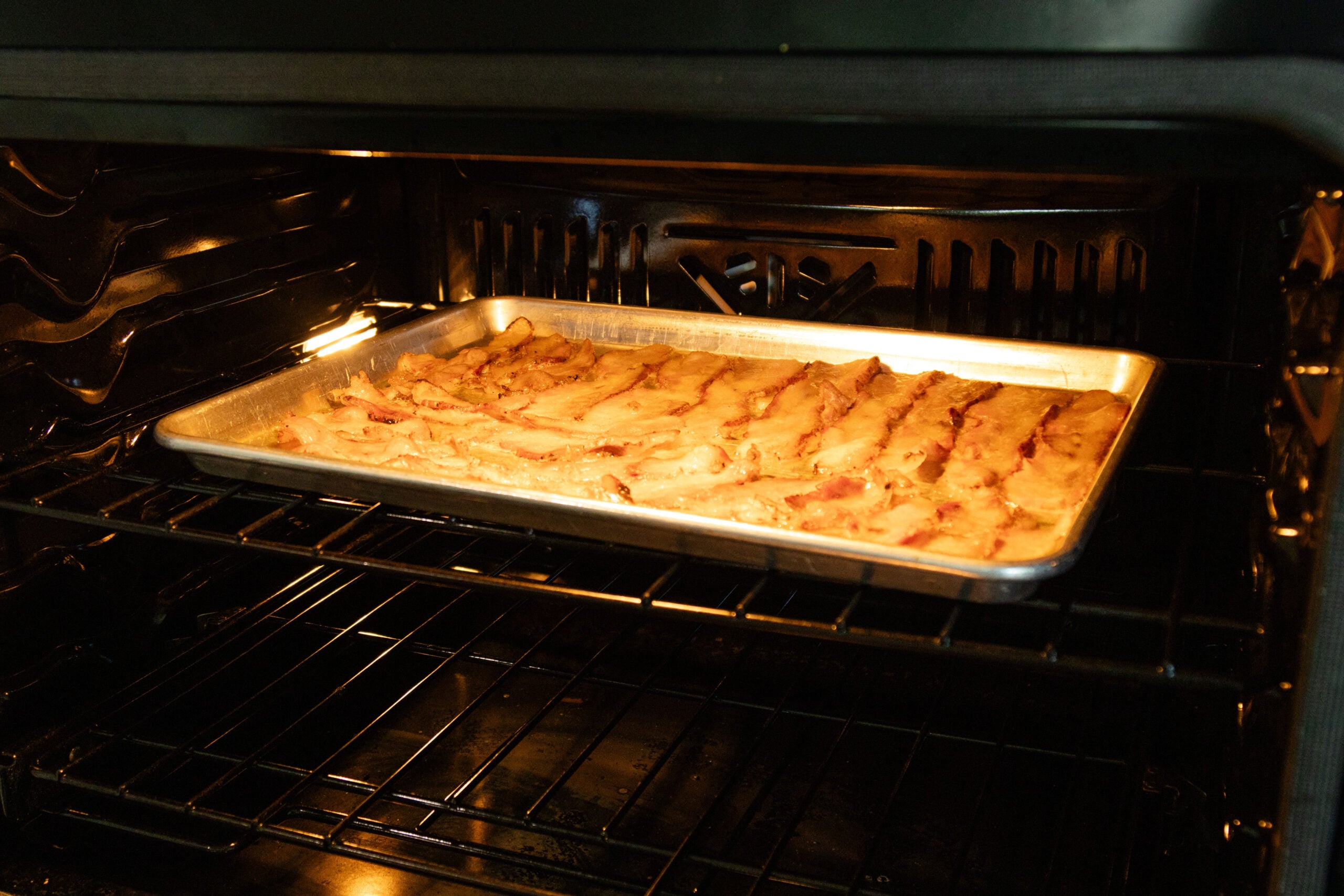 bacon frying on a pan in the oven