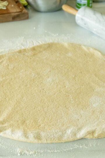 whole wheat pizza dough rolled out on the counter