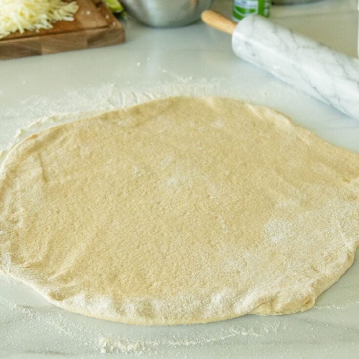 whole wheat pizza dough rolled out on the counter
