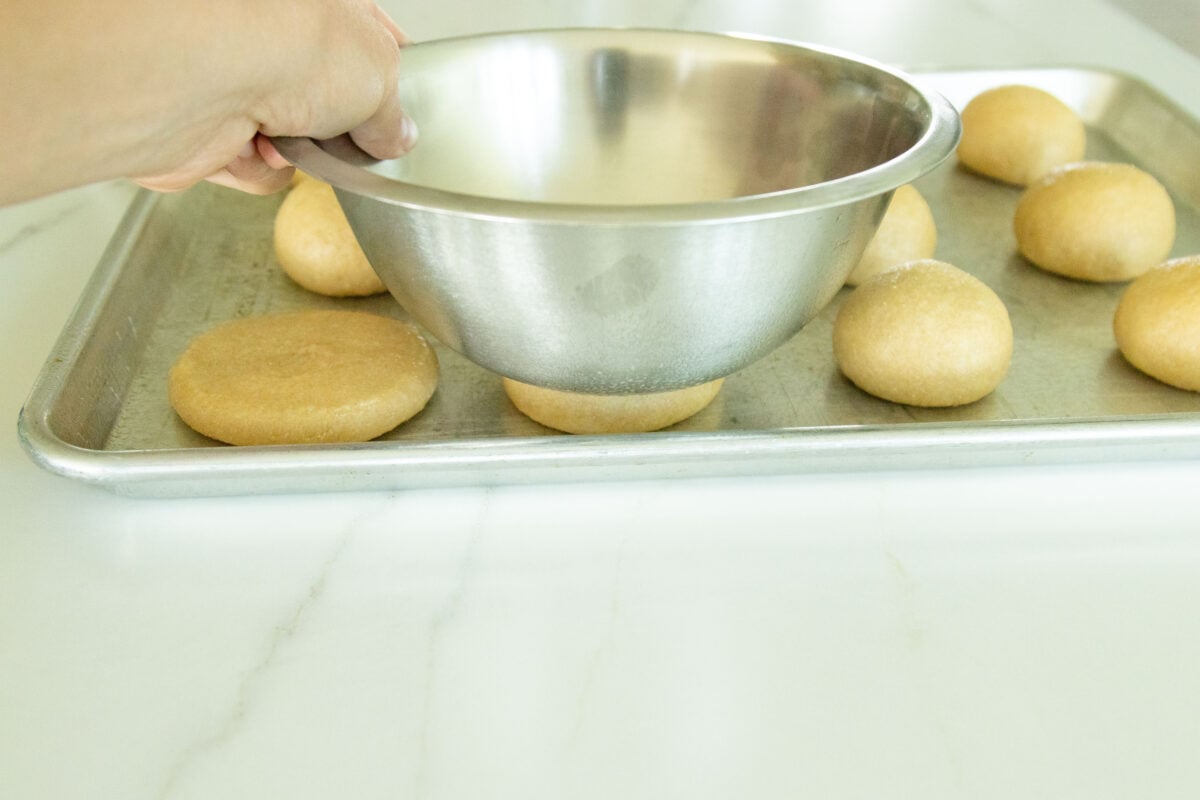 pressing the dough balls into buns with a bowl