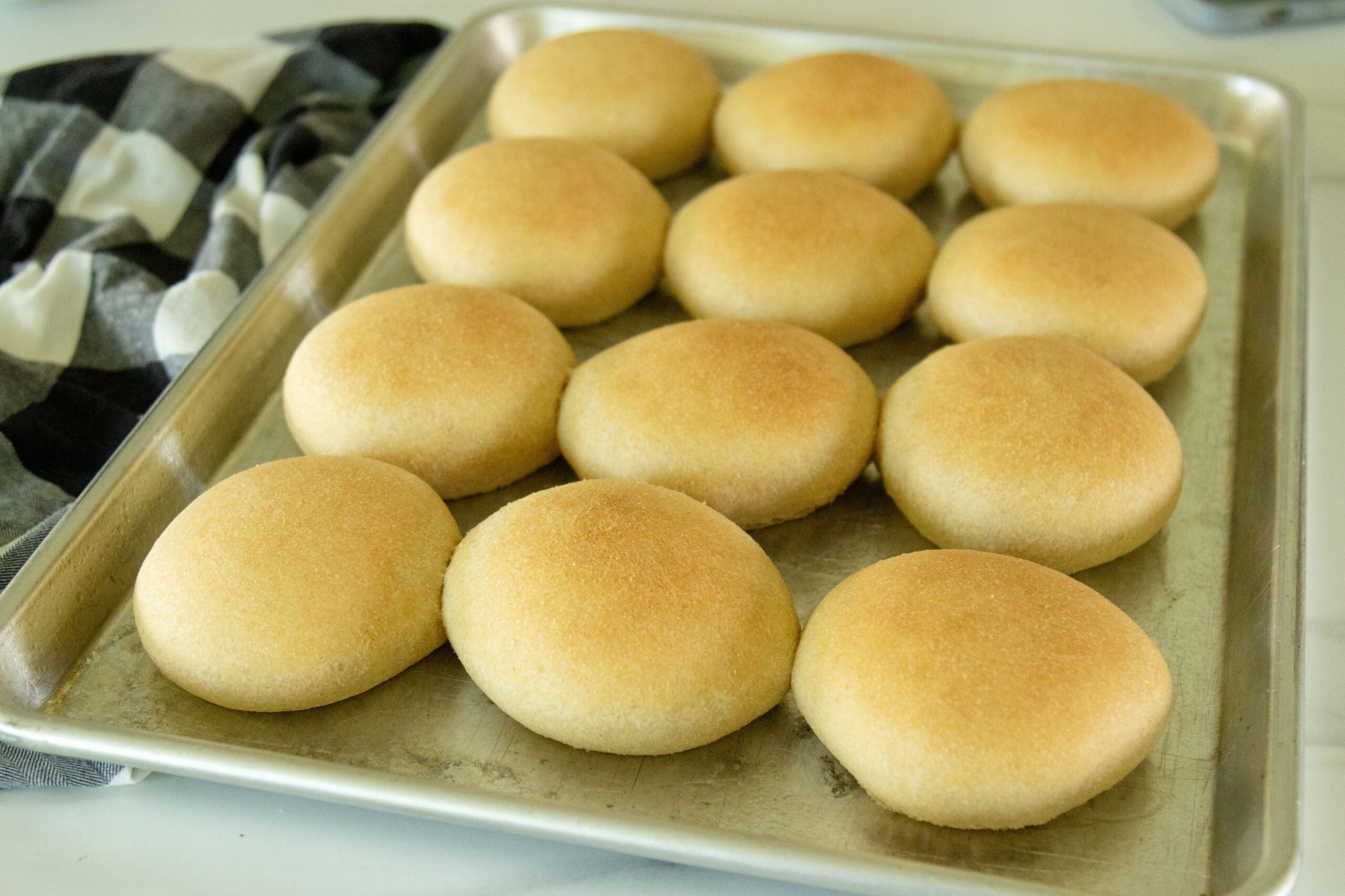 freshly baked fresh milled hamburger buns on a pan