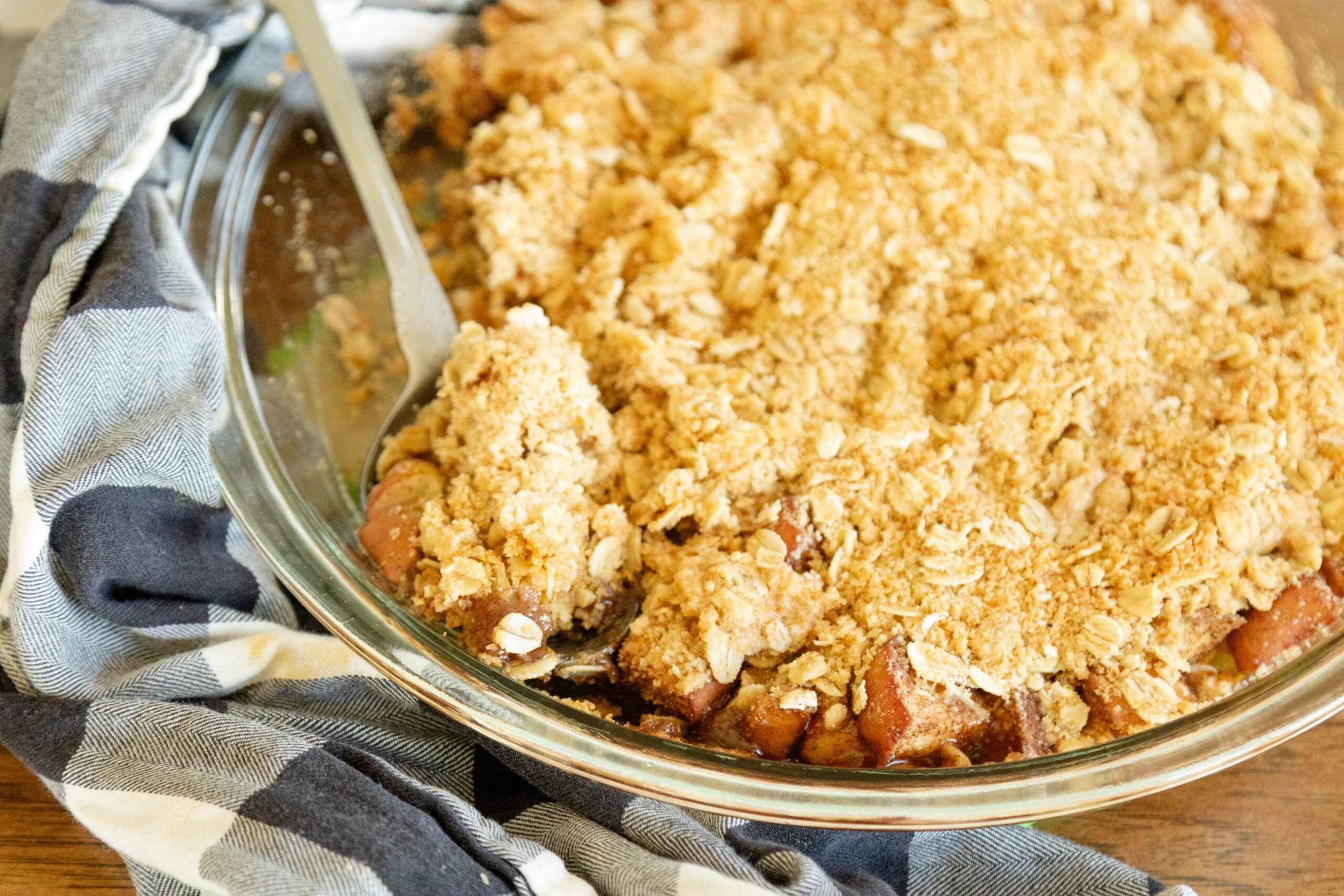 spoon scooping a serving of apple crisp put of the baking dish