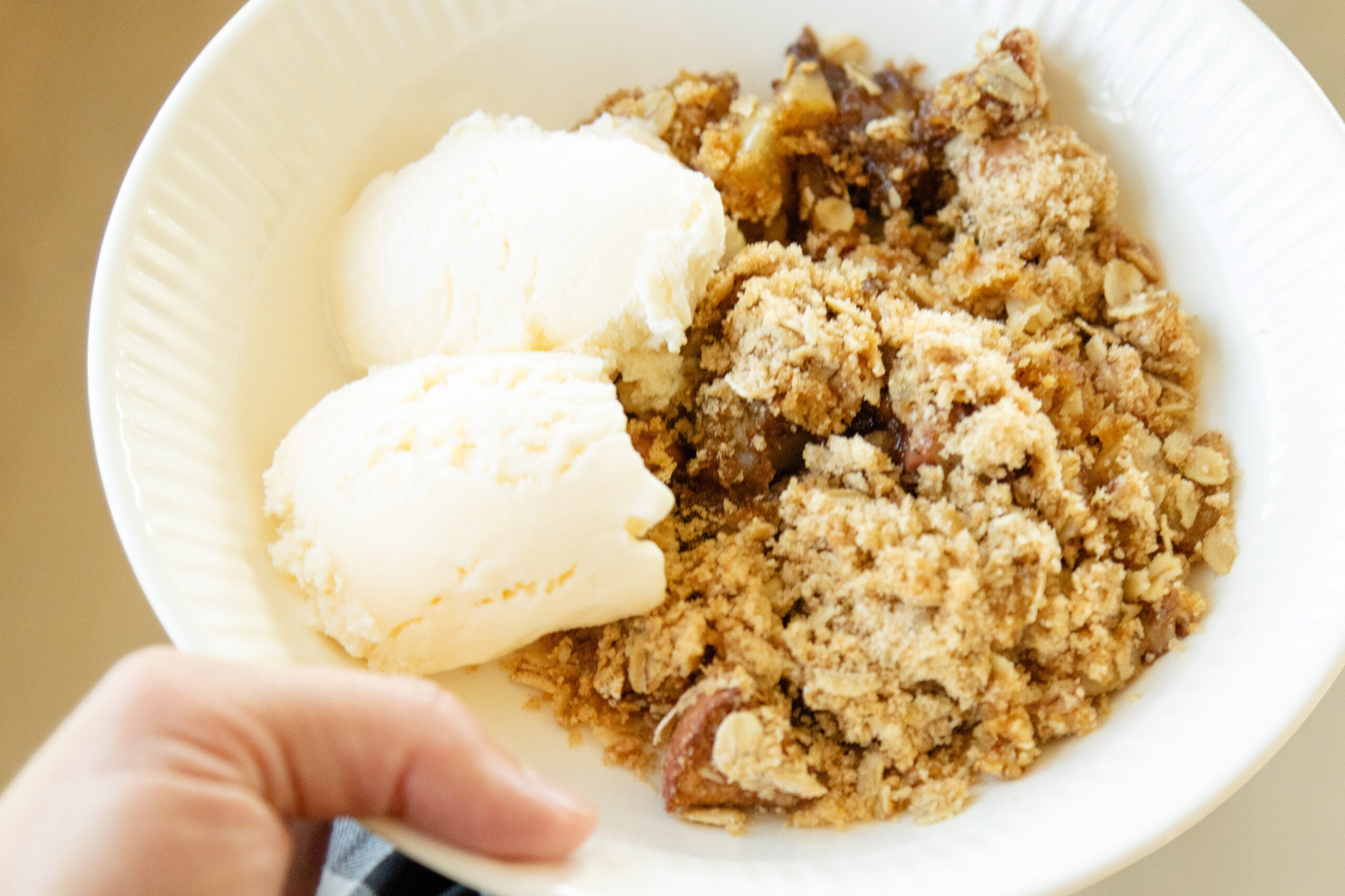 a serving of apple crisp and two blobs of ice cream in a bowl
