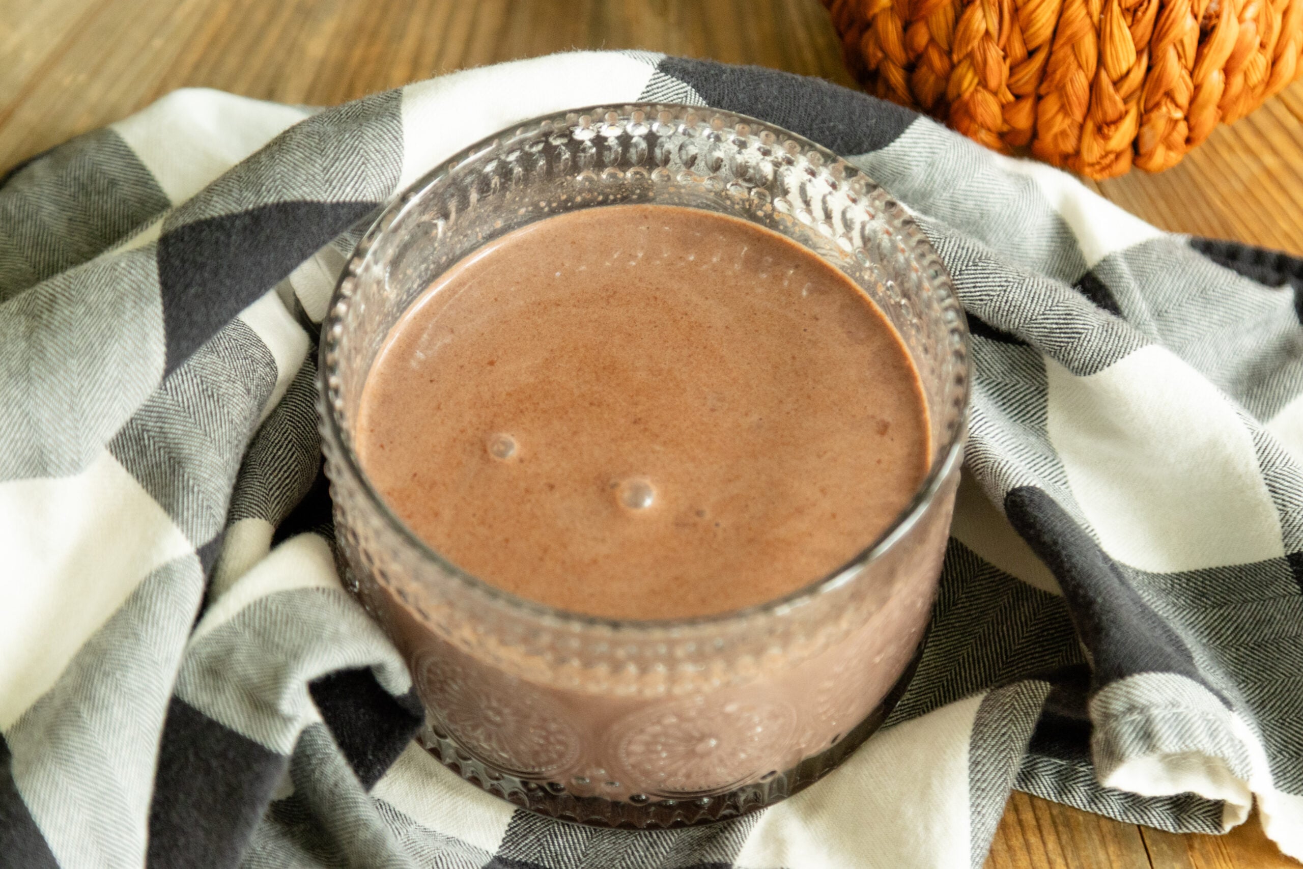a mug of pumpkin spice hot cocoa on a black and white checkered cloth